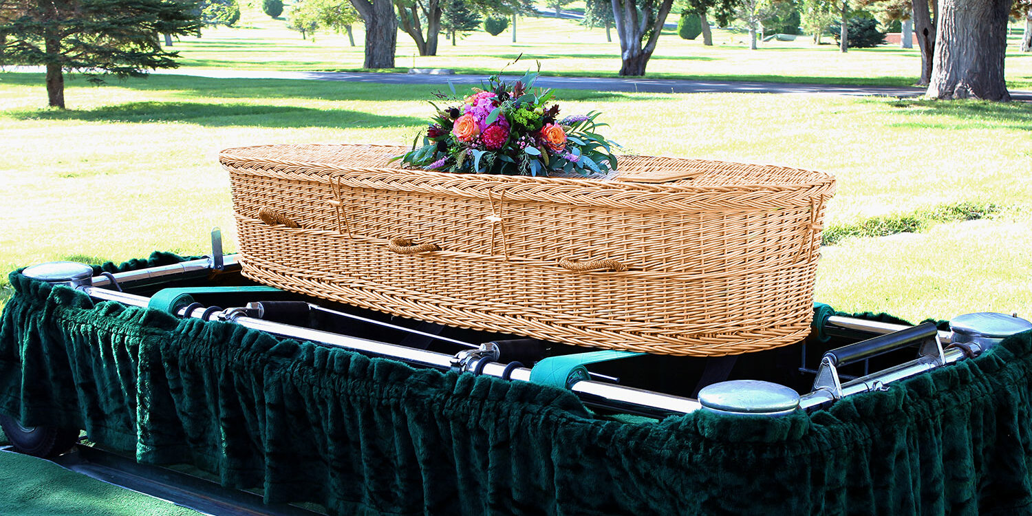 Willow wicker casket with floral spray on top.